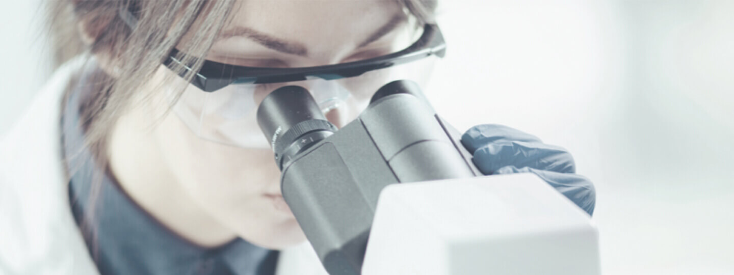 Doctora mira por el microscopio investigando