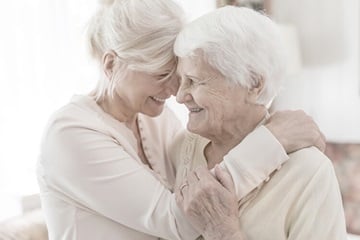 Mujer abrazándose con su madre mayor